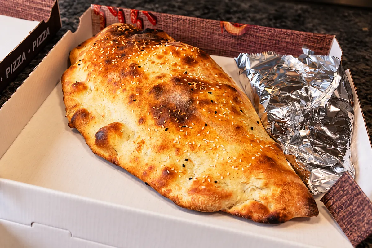 Goldbraun gebackene Teigtasche mit Sesam im Pizzakarton