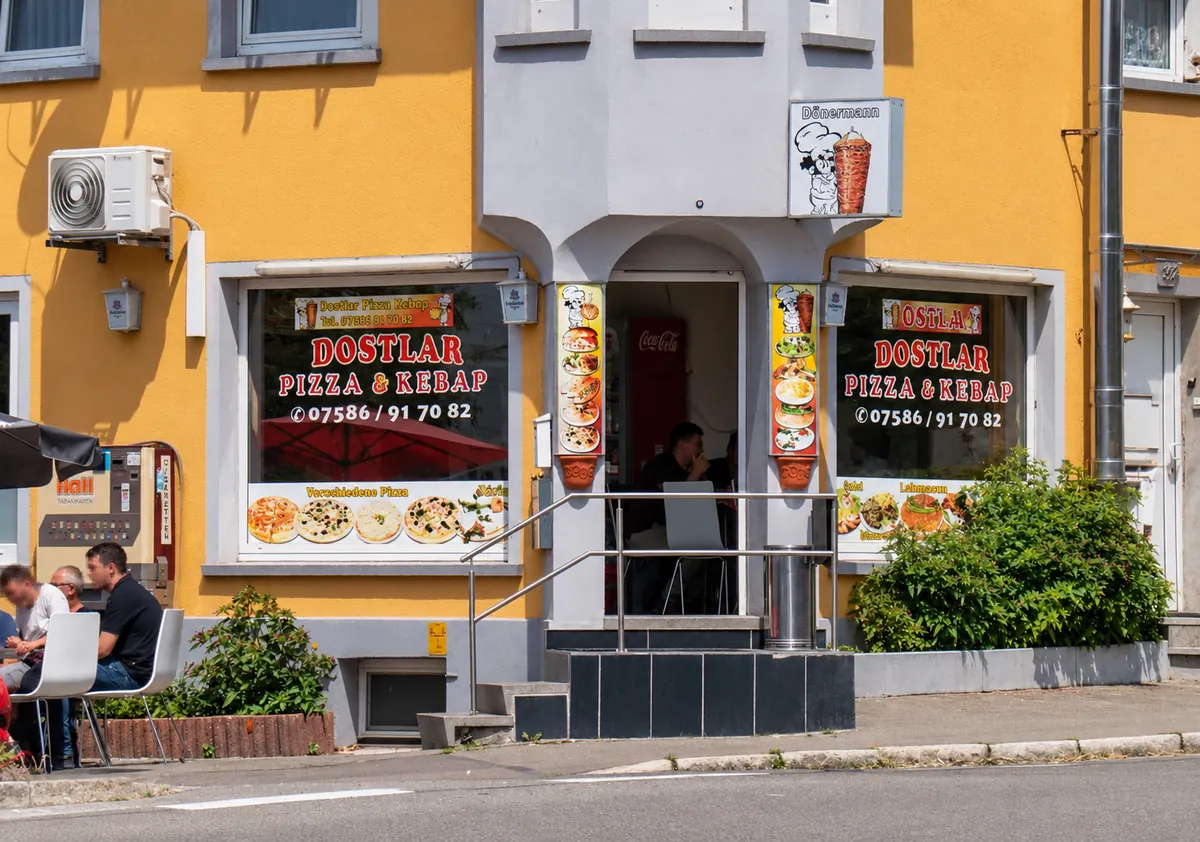 Das Dostlar Pizza & Kebap-Haus in der Ertinger Straße: gelbe Hauswand mit rotem Schriftzug auf den Schaufenstern